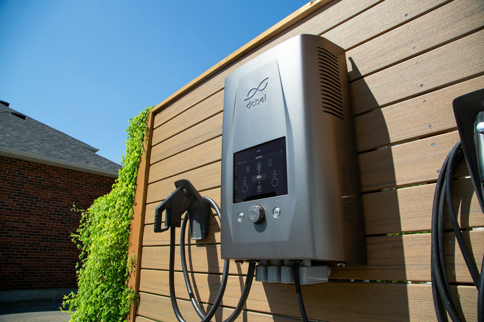 Wall-mounted Level 2 electric vehicle charger with its cable coiled on a hook
