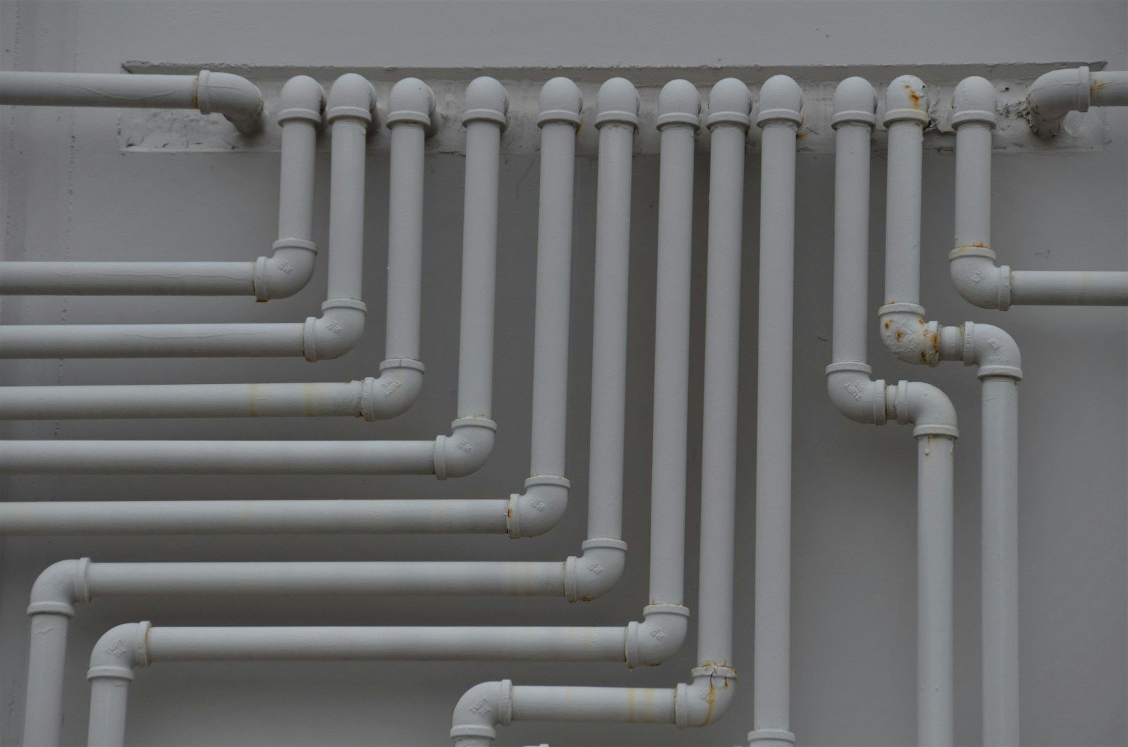 Close-up of parallel copper supply pipes secured to a wall with clips