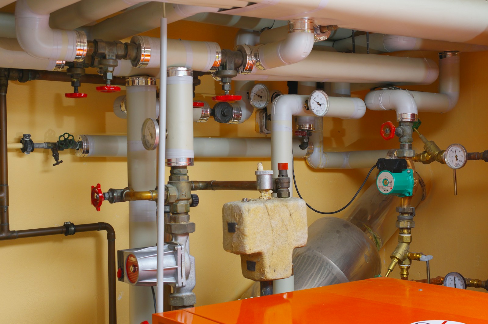 Run of insulated supply pipes and shutoff valves along a mechanical room wall